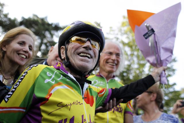 French centenarian Robert Marchand, foreground, reacts, after establishing a record for the fastest 100-year-old to cover 100km at the outdoor Velodrome track of Lyon, central France, Friday, Sept. 28, 2012. French cyclist Robert Marchand has ridden 100 kilometers (62 miles) in 4 hours, 17 minutes and 27 seconds. Doesn't sound fast? Consider this: Marchand is 100 years old. Setting off on his Trek racing bike around noon at a track in Lyon, Marchand covered the distance at an average pace of 23.3 kph (14.5 mph)  not far off the 24.251 kph pace he kept up to set the world hour record for his age group in Switzerland last February. (AP Photo/Laurent Cipriani)